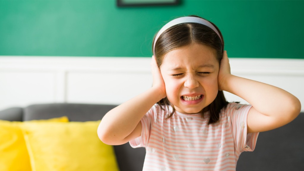 Child with autism experiencing sensory overload in a noisy environment with caregiver suppor